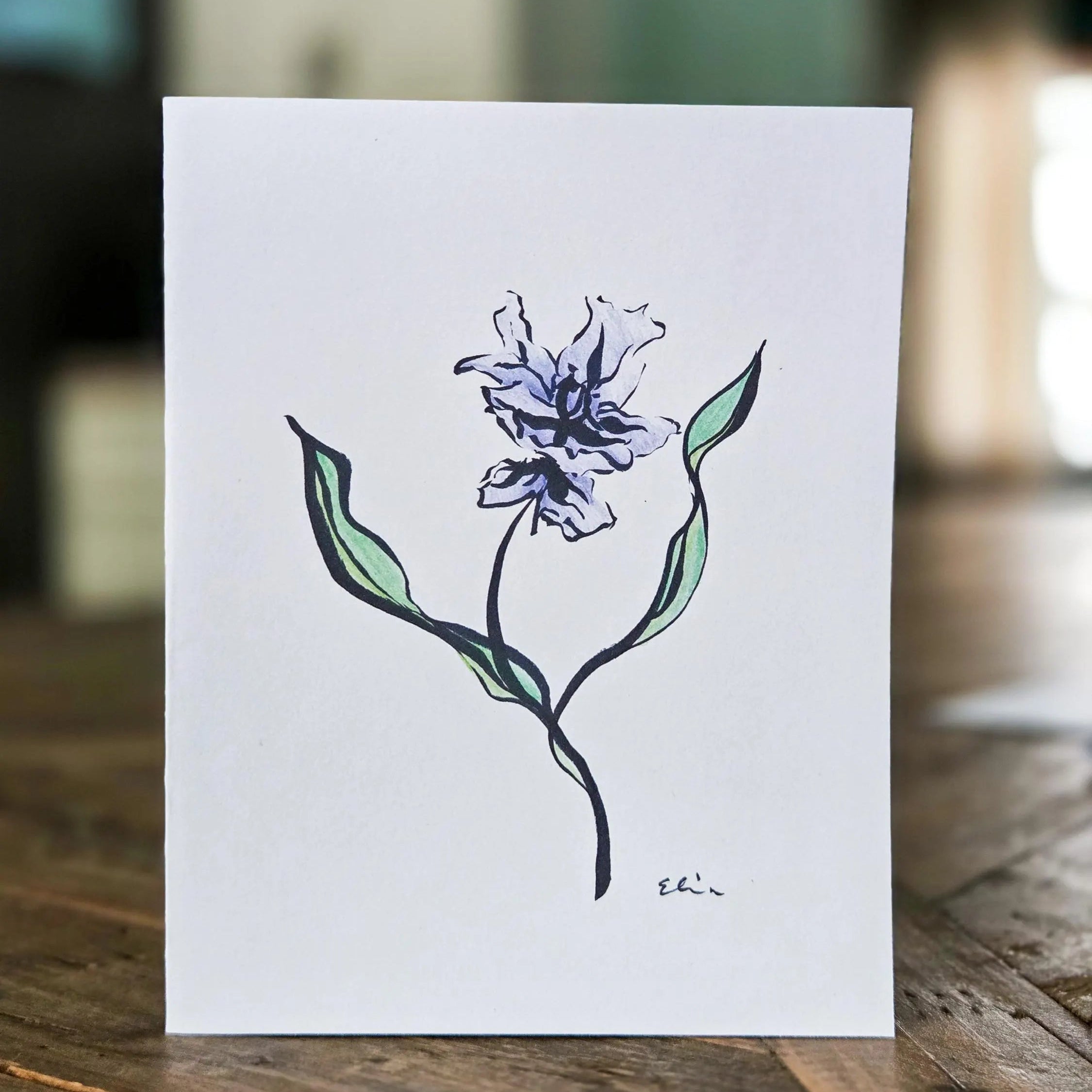 Card with a hand-drawn purple flower on a wooden surface