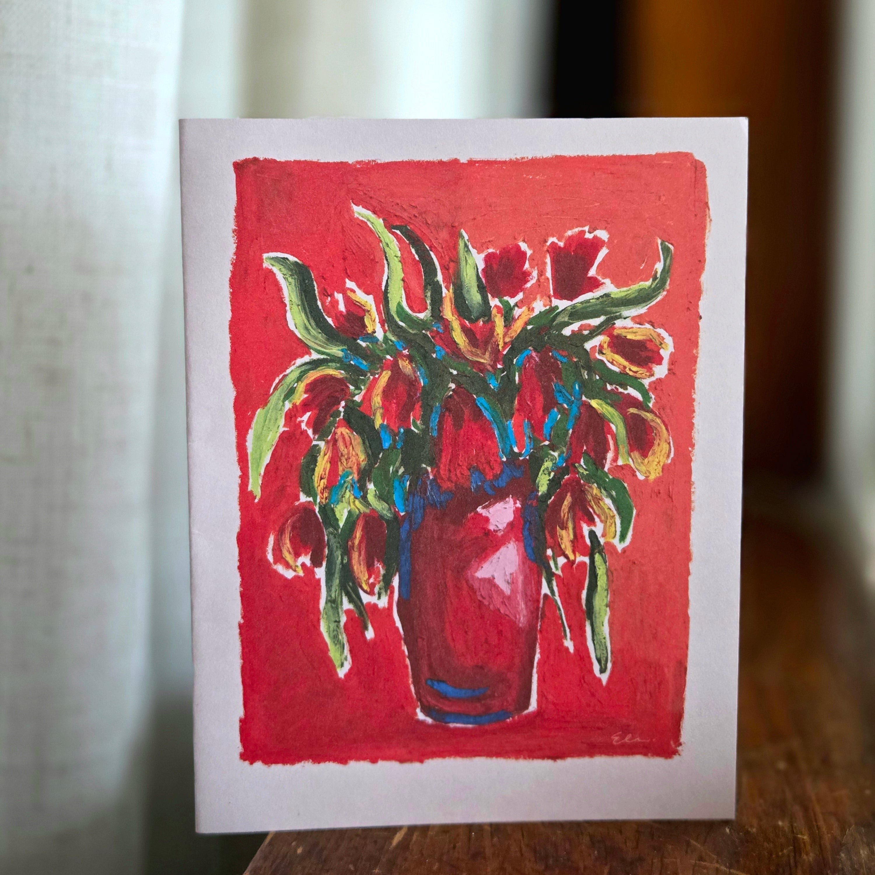 Small painting of a vase with flowers on a red background, placed on a wooden surface.