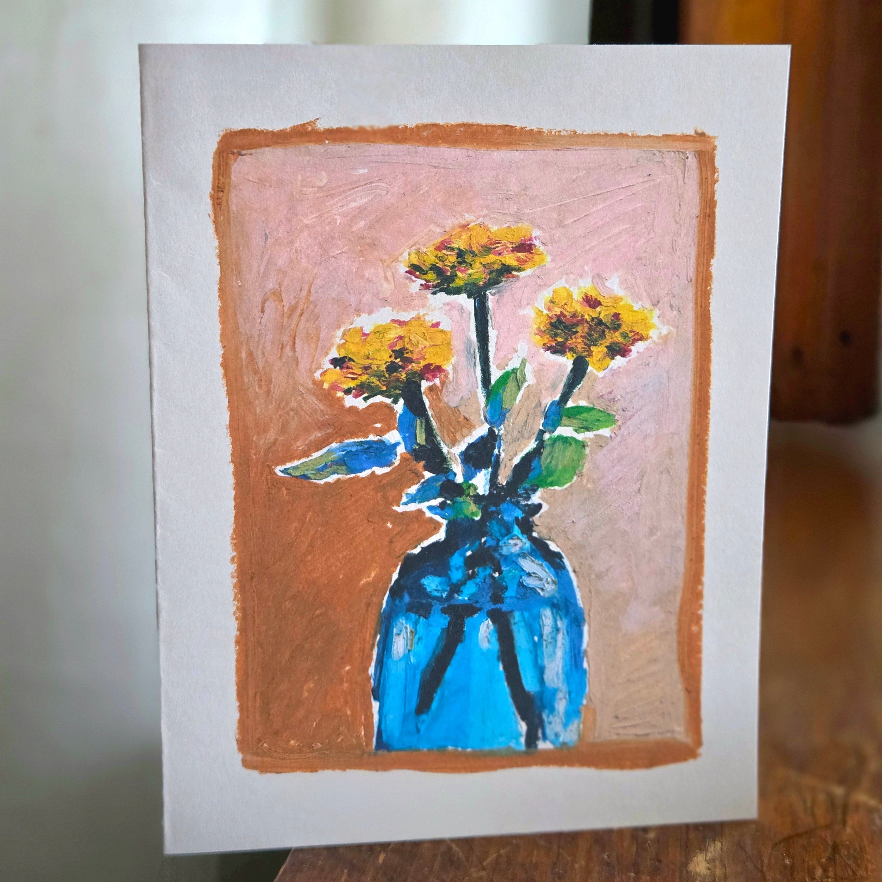 Card with a drawing of a blue vase with yellow flowers on a brown border.