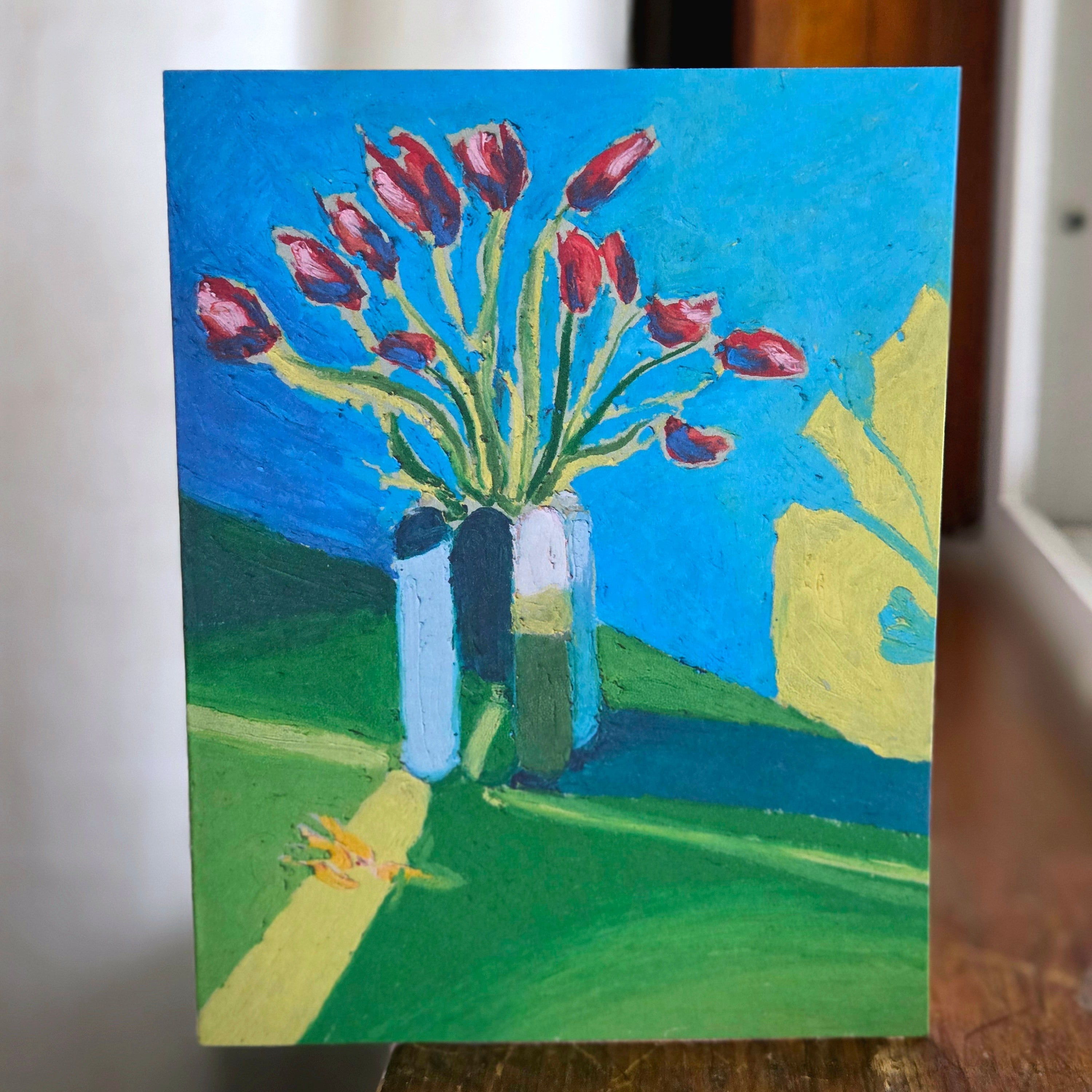 Small painting of red tulips in a vase on a blue background