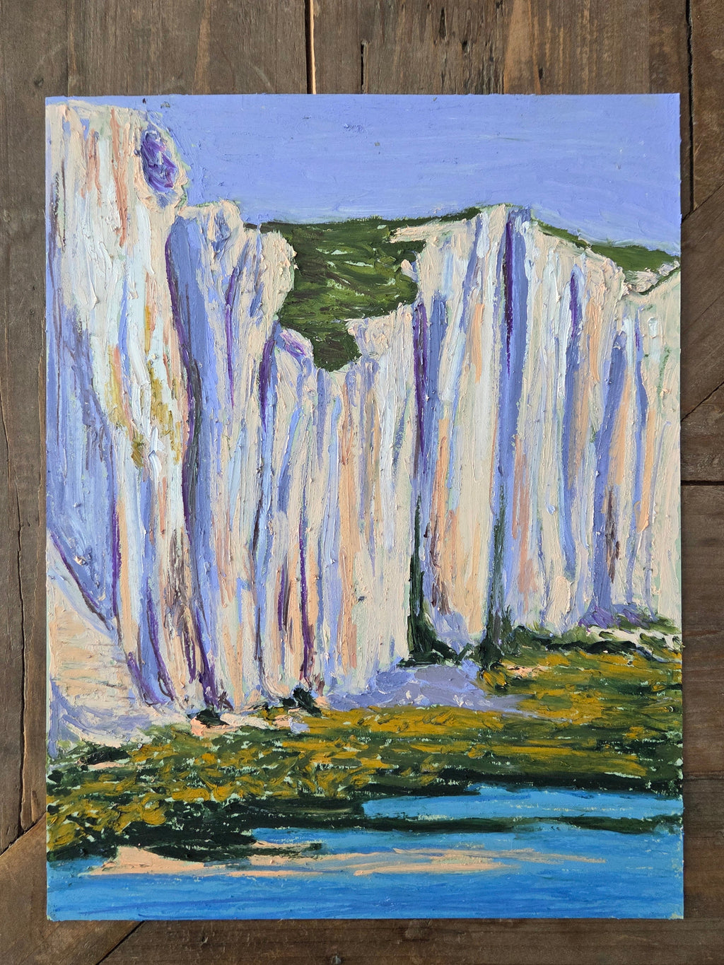 Abstract painting on a wooden surface with blue, green, and white colors.